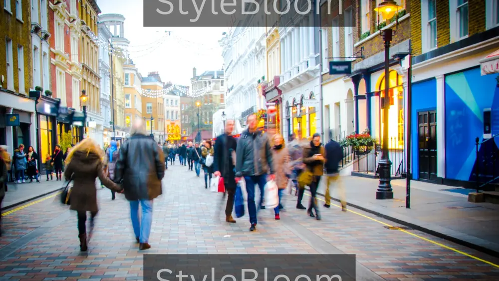 Shoppers in coats walking along a busy shopping street lined with shopfronts.