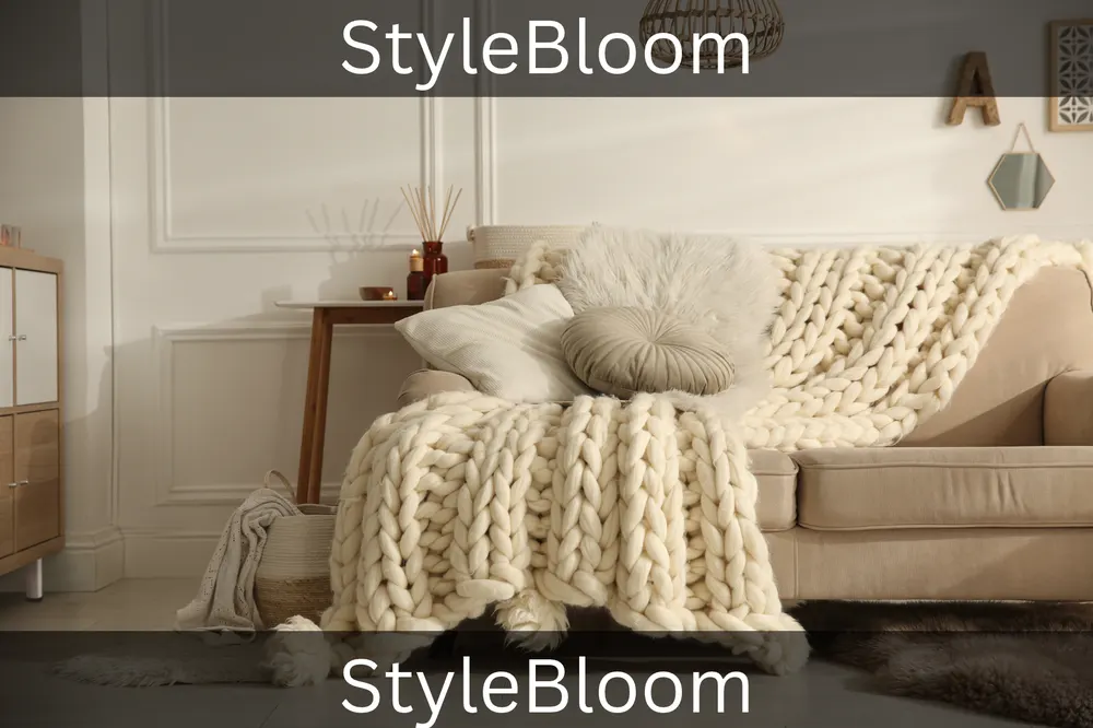 A chunky cream knit blanket draped over a beige sofa with pillows
