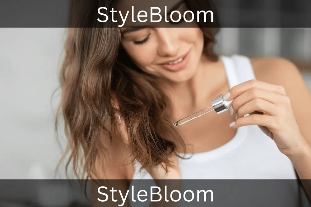 A woman holding a dropper with a drop of serum above the ends of her wavy, frizzy hair