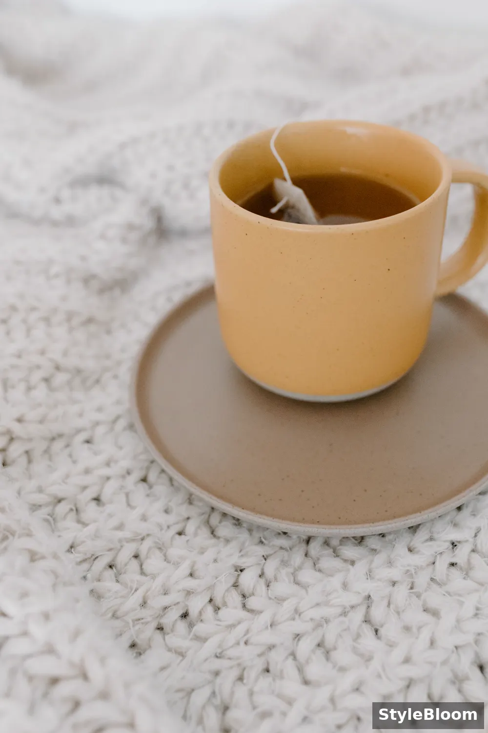 A cup of tea with a teabag on a knitted blanket