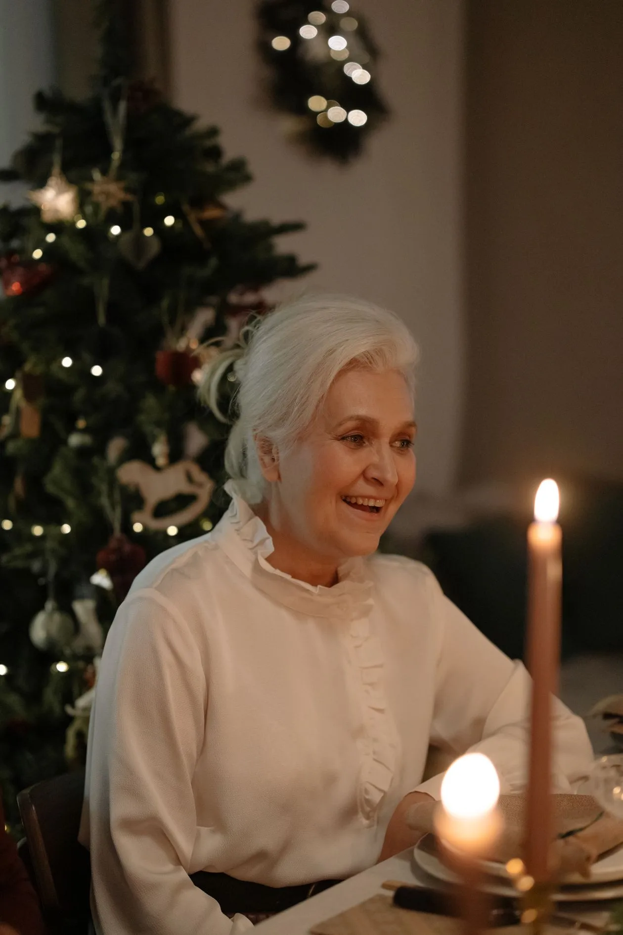 A smiling nan at a candlelit Christmas table — time together is the gift for a nan who has everything