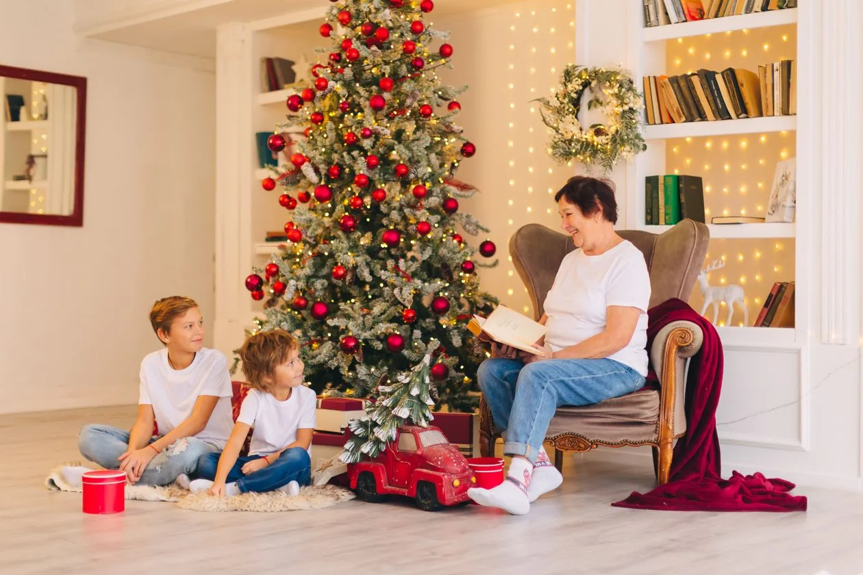A grandmother reading to her grandchildren beside the Christmas tree — personal Christmas gifts for Nan